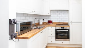 A kitchen with white cabinets, a wooden countertop, a microwave, a toaster, and an oven. - 3BR Thames Retreat Heathrow 10min Train 5min (Egham)