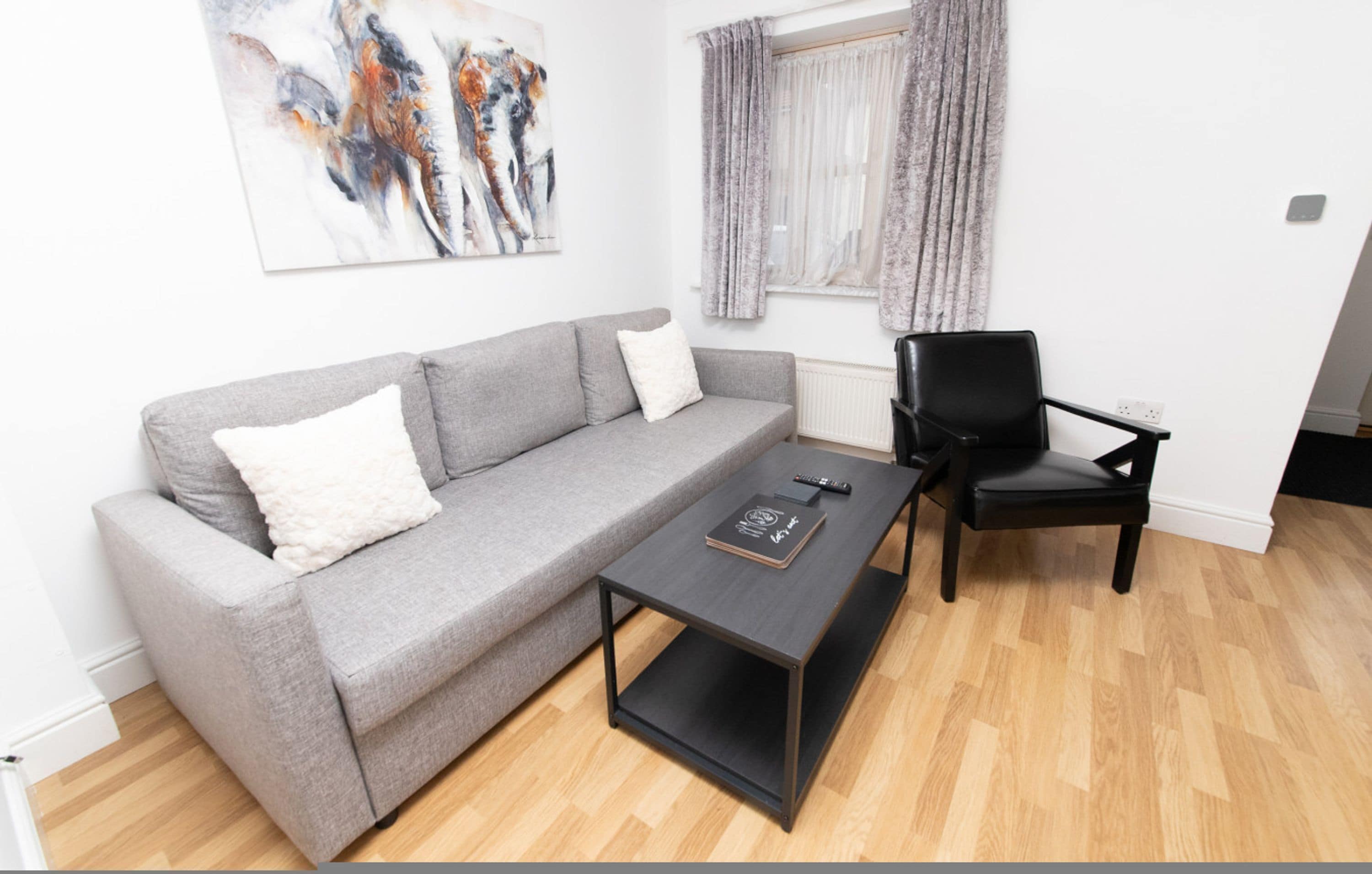 Un salon moderne avec un canapé gris, une table basse noire et un fauteuil noir.
