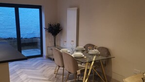 A dining area with a glass table, chairs, and a view of the outside. - London 2BR Retreat With Free Parking City Access (London)