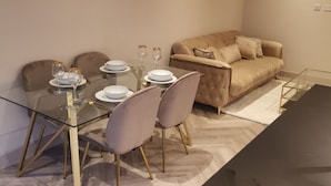 A modern living room with a glass dining table, beige sofa, and a black coffee table. - London 2BR Retreat With Free Parking City Access (London)