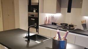 A modern kitchen with a black countertop, stainless steel appliances, and a built-in oven. - London 2BR Retreat With Free Parking City Access (London)