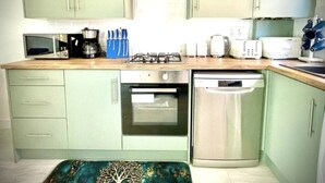 Een keuken met een magnetron, kookplaat, oven en vaatwasser.