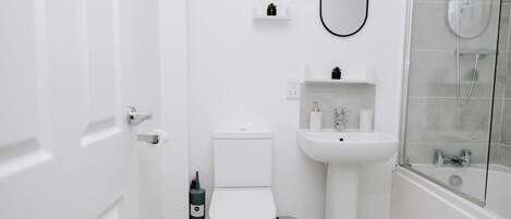 A bathroom with a toilet, sink, and shower.