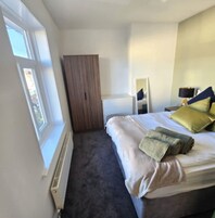 Un dormitorio con cama, armario, espejo y ventana.