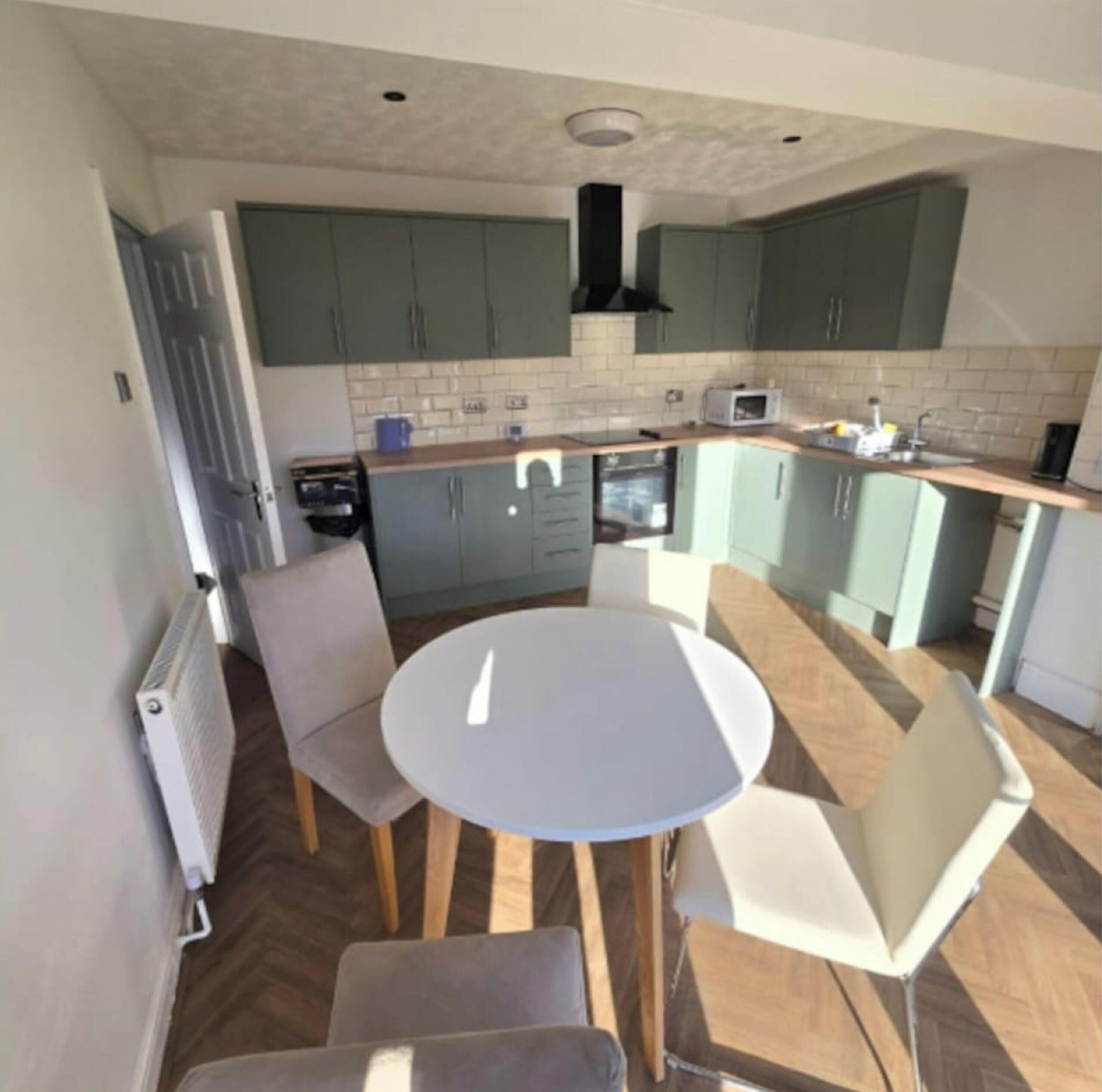 A compact kitchen with a round table and chairs, a microwave, and a sink.
