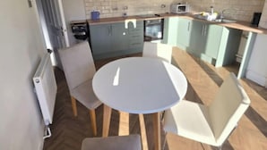 A compact kitchen with a round table and chairs, a microwave, and a sink. - West Midlands Home - 3BR w Free Parking and Wifi (Dudley)