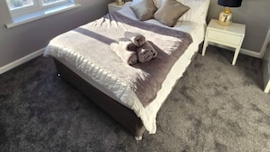 A bedroom with a bed, two bedside tables, a window, and a view of houses outside. - West Midlands Home - 3BR w Free Parking and Wifi (Dudley)