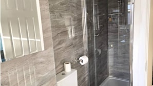 A modern bathroom with a glass-enclosed shower, a toilet, and a mirror. - West Midlands Home - 3BR w Free Parking and Wifi (Dudley)