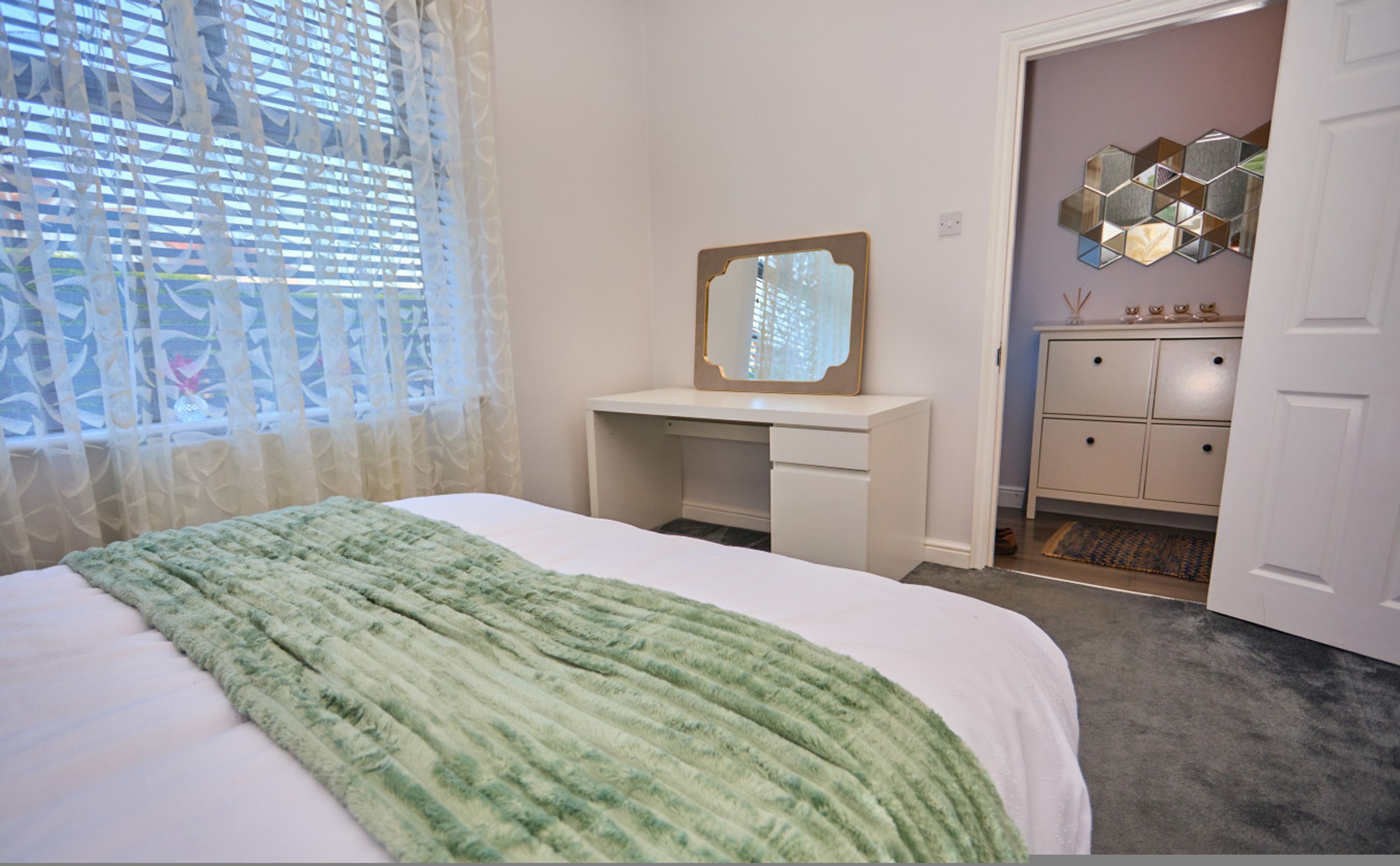 Une chambre à coucher avec un lit, un bureau, une commode et un miroir.