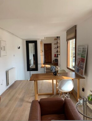 Ein modernes Wohnzimmer mit einem Holzesstisch, einem braunen Ledersofa und einem Glastisch.