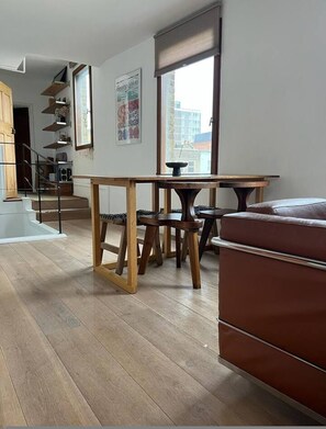 Ein modernes Wohnzimmer mit einem Holzesstisch, einer Couch und einer Treppe, die zu einer oberen Etage führt.