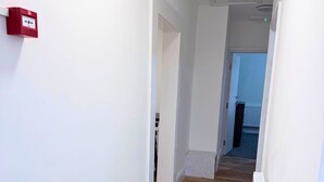 Un pasillo con paredes blancas, suelo de madera y un radiador a la vista.