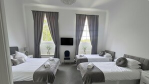 A hotel room with two beds, a TV, and a small seating area. - Room 3 - Manor Park Country House Wales Perfect for Families (Swansea)