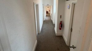 A narrow hallway with carpeted floors, white walls, and a ceiling light. - Room 3 - Manor Park Country House Wales Perfect for Families (Swansea)