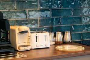 Eine Küche mit einer Bosch-Kaffeemaschine, einem Tassimo-Toaster und Edelstahlbehältern auf einer Holzarbeitsfläche.