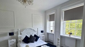 A bedroom with a white four-poster bed, a chandelier, a window with a view, and a radiator. - Room 4 Manor Park Country House in Swansea Sleeps 2 (Swansea)