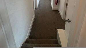 A narrow hallway with carpeted floors, white walls, and a ceiling light fixture. - Room 4 Manor Park Country House in Swansea Sleeps 2 (Swansea)