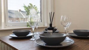 Una mesa de comedor con cuencos, copas de vino y una botella de agua.