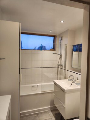 Ein modernes Badezimmer mit Badewanne, Dusche, Waschbecken und einem Fenster.
