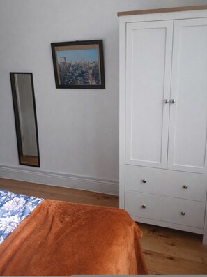 A bedroom with a bed, a wardrobe, a mirror, and a framed cityscape picture on the wall. - Spacious 2BR Ground-floor Flat w Free Parking Palmers Green (London)