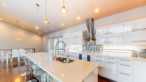 A modern kitchen with a large island, stainless steel appliances, and pendant lighting. - Spokane River Retreat (Coeur d'Alene)