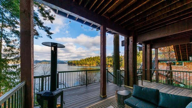 A covered deck with a view of a lake, outdoor seating, and a fire pit. - Deja View in Hayden With 5 Bedrooms and 6 Bathrooms (Hayden)