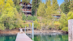 A wooden dock extending into a clear body of water, surrounded by trees and a multi-story building with balconies. - Deja View in Hayden With 5 Bedrooms and 6 Bathrooms (Hayden)