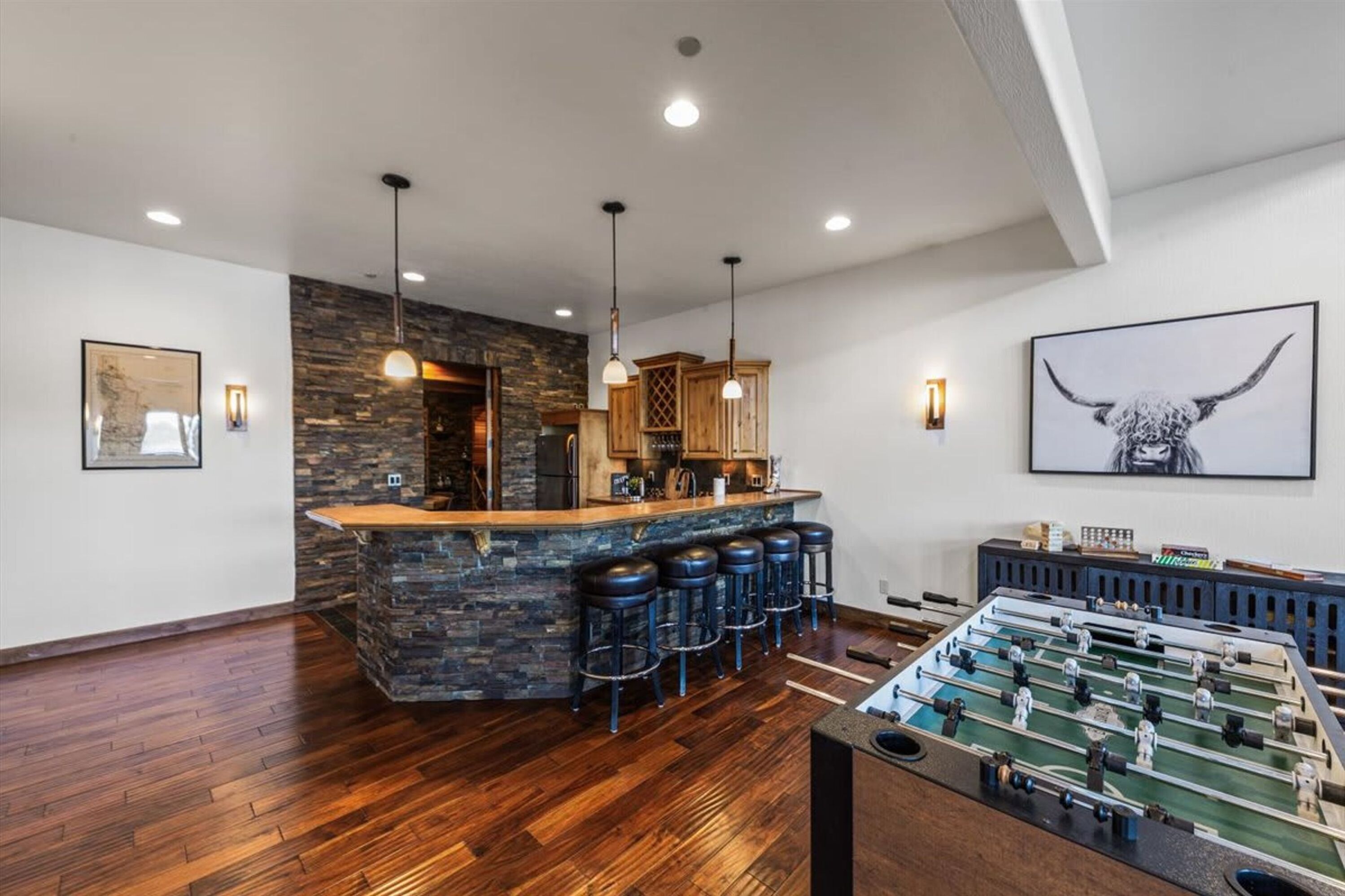A bar area with stools, a foosball table, and a stone accent wall.