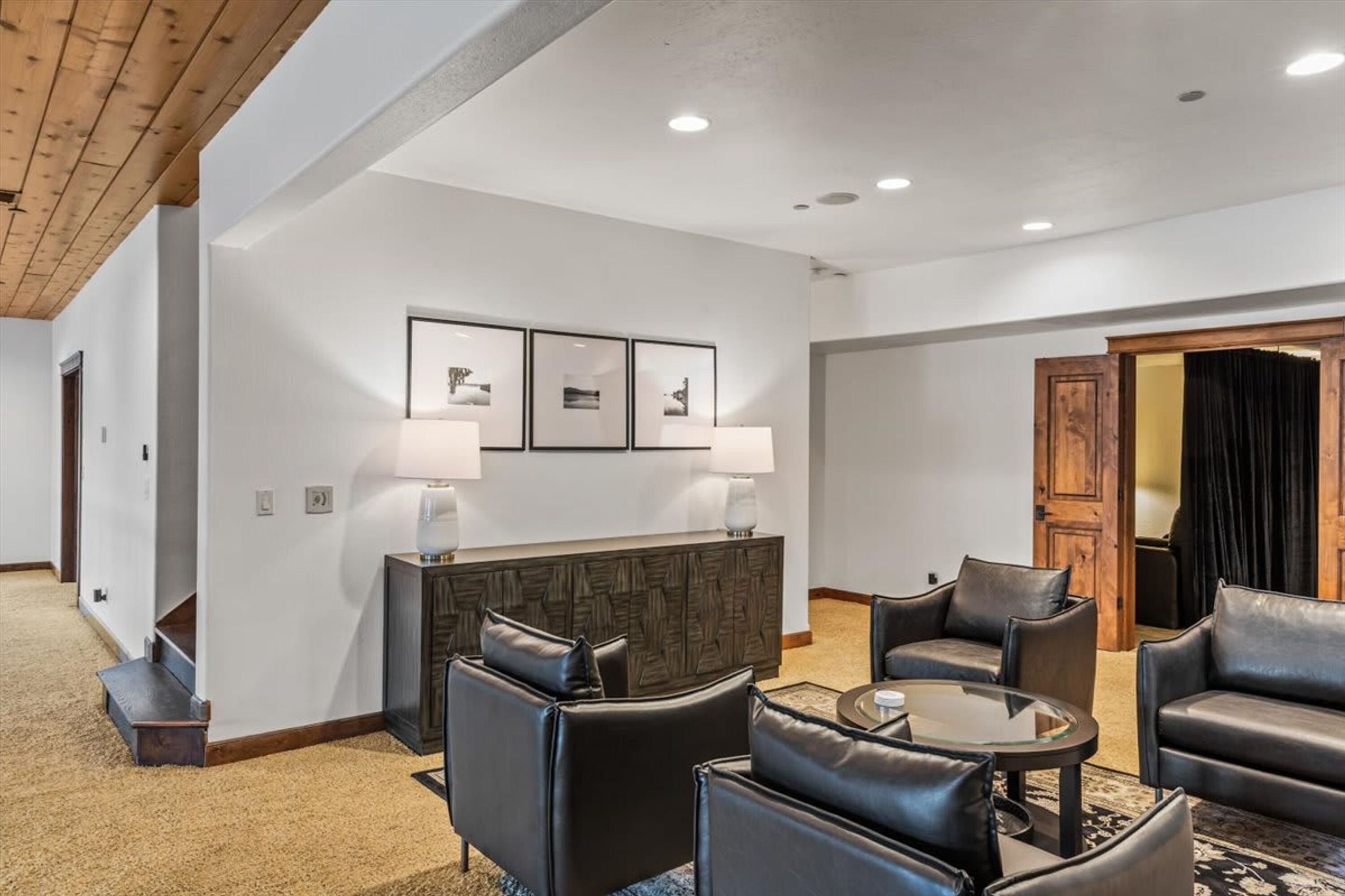 Un hall d’hôtel avec un comptoir d’accueil, des tableaux encadrés, des fauteuils en cuir et une porte en bois.