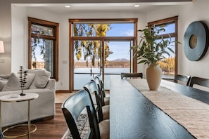 A dining area with a view of a lake, a sofa, and a clock on the wall. - Deja View in Hayden With 5 Bedrooms and 6 Bathrooms (Hayden)