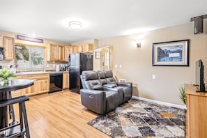 A modern kitchen with wooden cabinets, a black refrigerator, and a black leather recliner. - Bungalow on Boyd in Coeur d Alene (Coeur d'Alene)