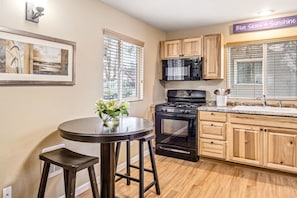 A kitchen with wooden cabinets, a black stove, and a microwave. - Bungalow on Boyd in Coeur d Alene (Coeur d'Alene)