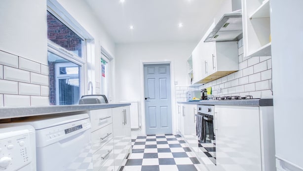 A modern kitchen with white cabinets, a checkered floor, and a blue door. - Modern 3-bed Home Sleeps 6 With Parking Fast Wifi Perfect for Contractors Long Stays (St Helens)