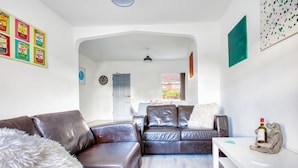A modern living room with leather sofas, a white coffee table, and a dining area with a white table and chairs. - Modern 3-bed Home Sleeps 6 With Parking Fast Wifi Perfect for Contractors Long Stays (St Helens)
