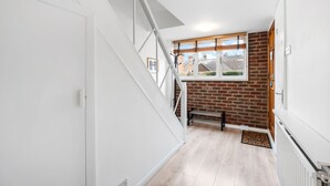 A staircase leading to a room with a brick wall and a window. - Central Horsham 5BR Home Parking Pets Allowed (Horsham)