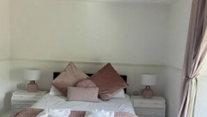 A bedroom with a bed, two bedside tables, and a nightstand. - Room 2 Manor Park Country House in Swansea (Swansea)