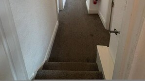 A narrow hallway with carpeted stairs, white walls, and a ceiling light. - Room 2 Manor Park Country House in Swansea (Swansea)