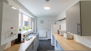 A compact kitchen with a window, a clock, a radiator, and a toaster. - Alice Street Retreat - 1BR Sleeps 4 Street Parking (South Shields)