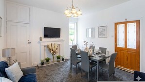 A dining area with a fireplace, a television, and a dining table set for four. - Alice Street Retreat - 1BR Sleeps 4 Street Parking (South Shields)
