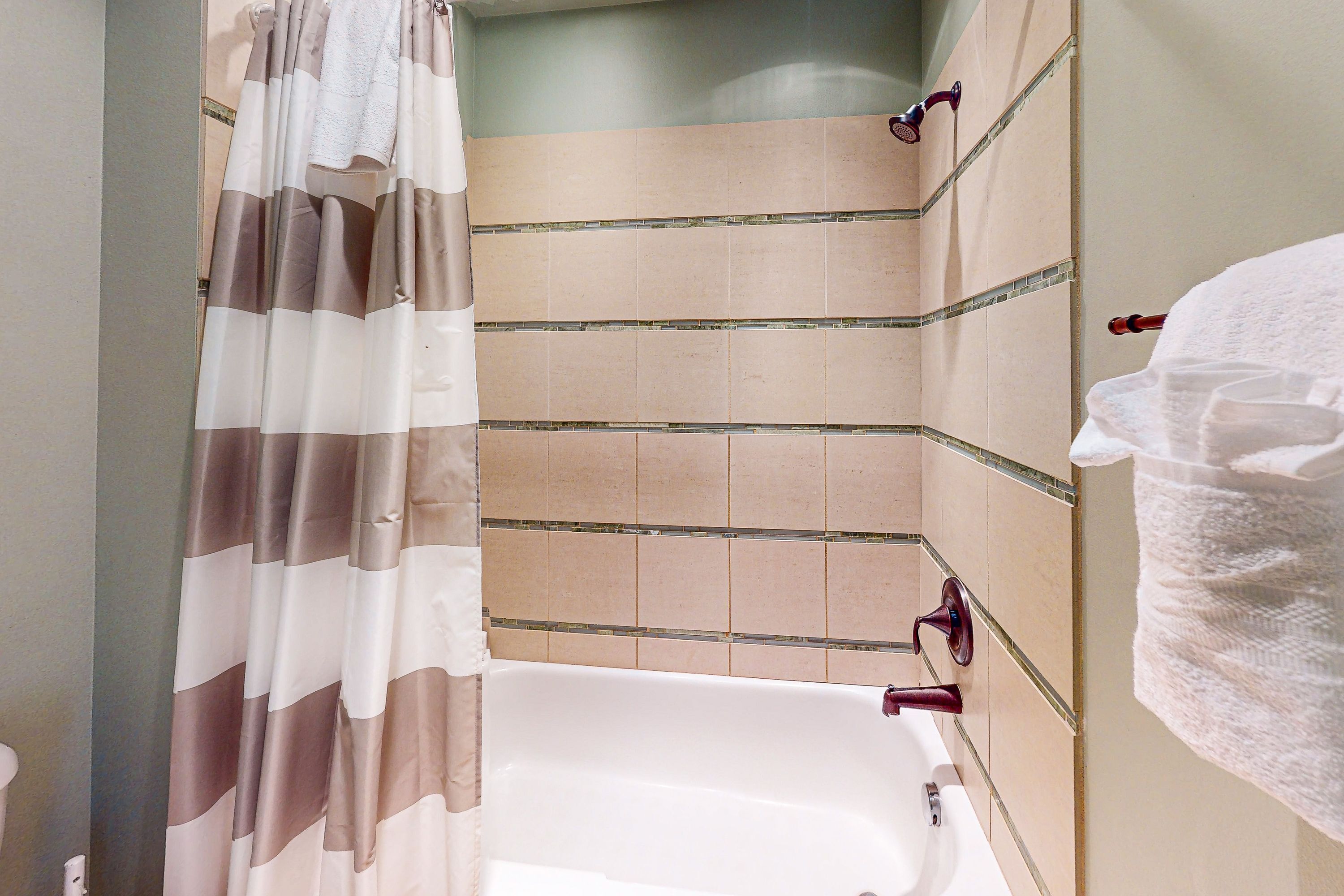 A bathroom with a bathtub, shower curtain, and tiled walls.