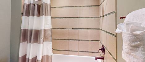 A bathroom with a bathtub, shower curtain, and tiled walls.