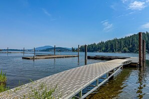 A wooden dock extending into calm water with a clear sky and distant mountains. - Beautiful Lakefront Custom (Coeur d'Alene)