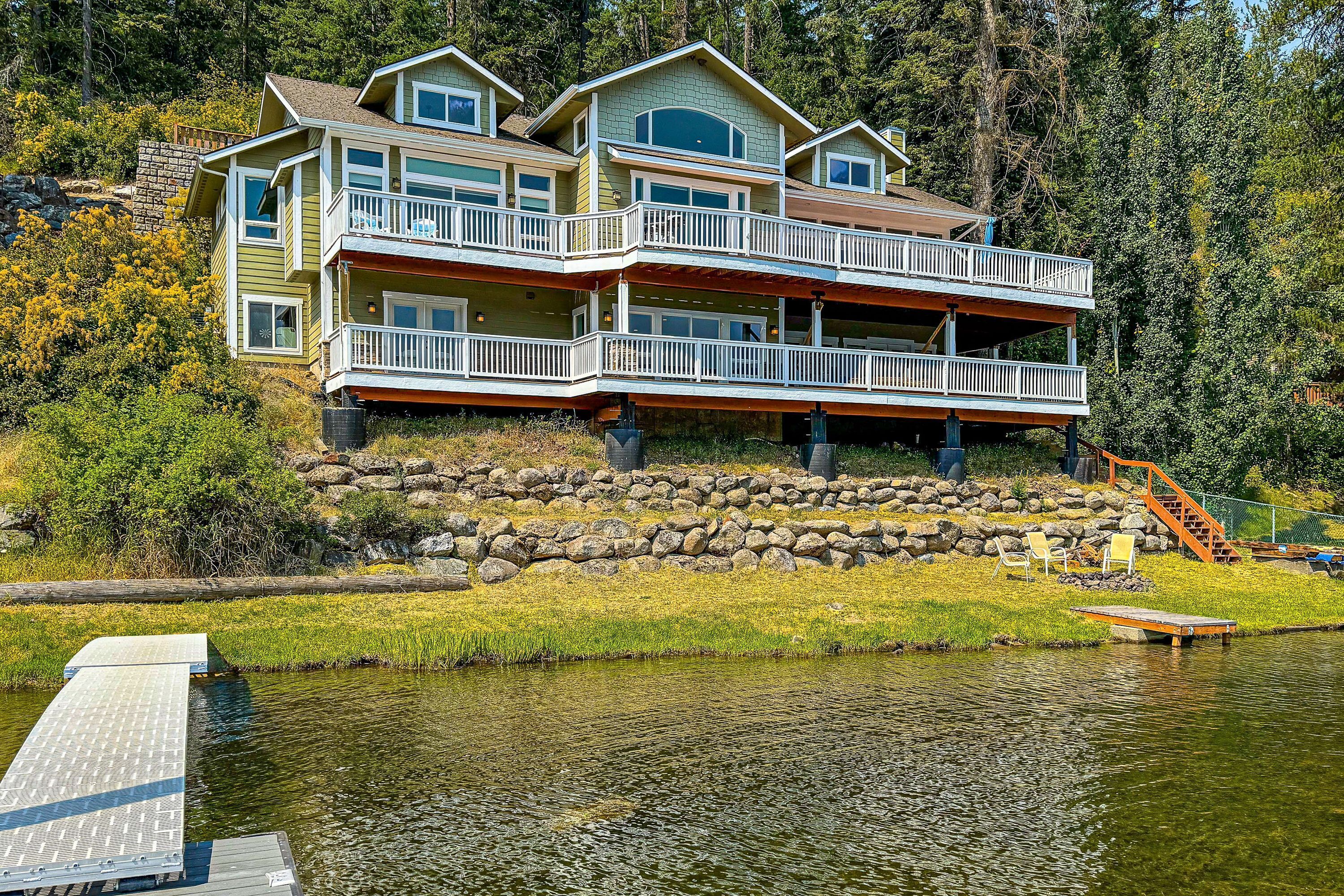 A multi-story house with balconies, a dock, and a stone retaining wall.
