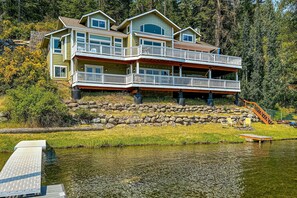 A multi-story house with balconies, a dock, and a stone retaining wall. - Beautiful Lakefront Custom (Coeur d'Alene)