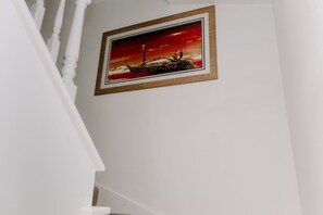 Escadaria com grades brancas e um quadro emoldurado retratando um pôr do sol.