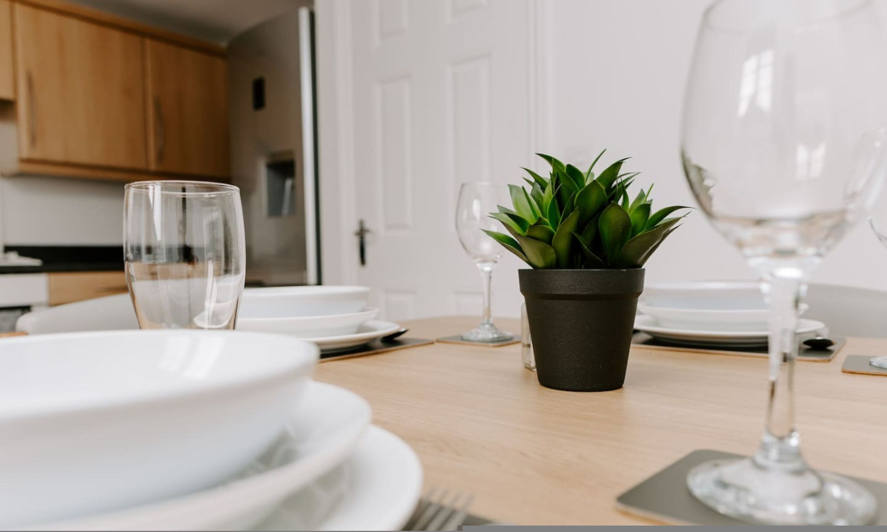 A dining table with plates, glasses, and a potted plant.