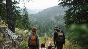 A family walking on a forest trail surrounded by trees and rocks.