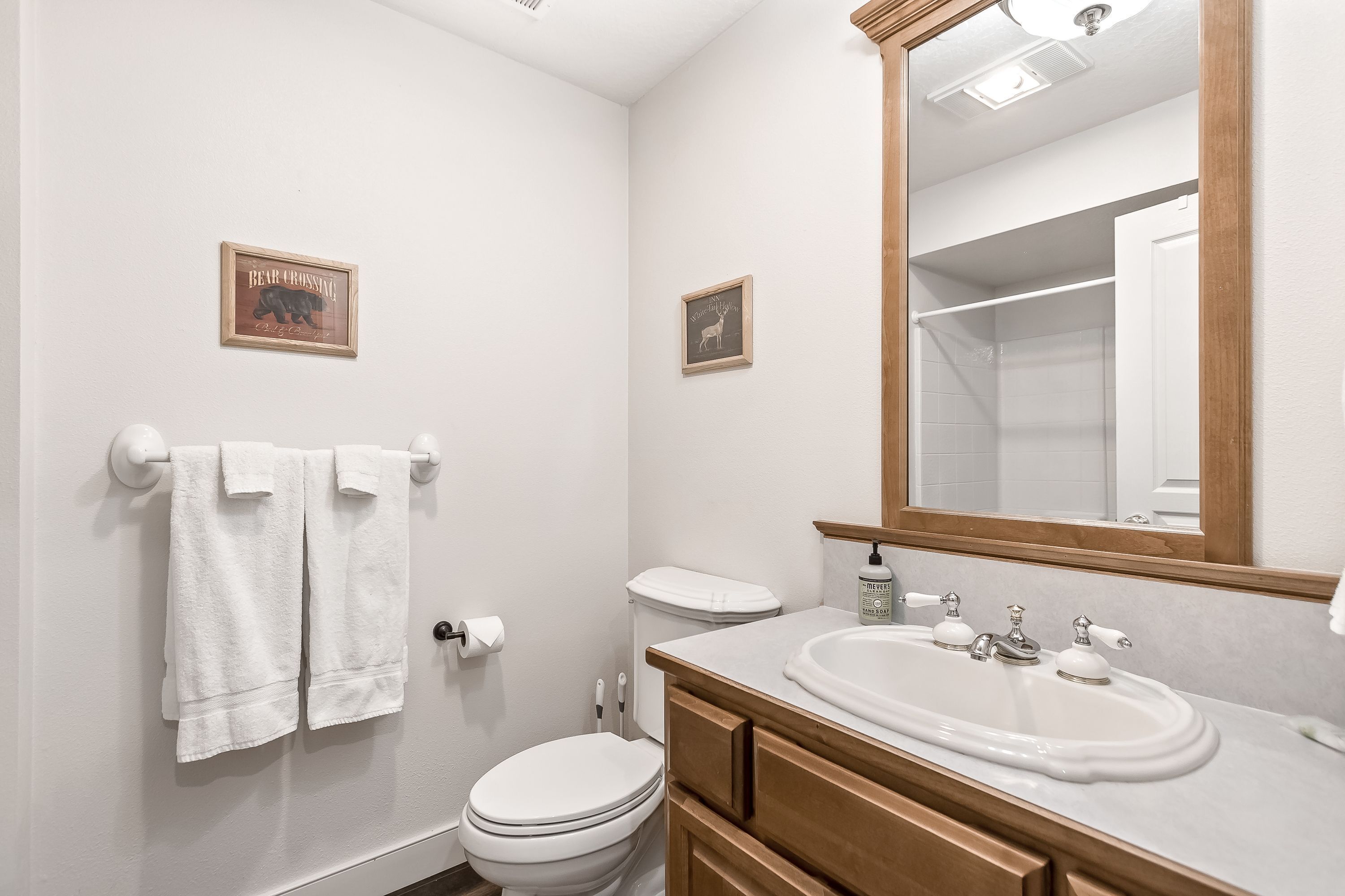 A bathroom with a toilet, sink, mirror, towel rack, and two wall-mounted signs.