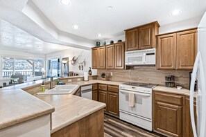 A modern kitchen with wooden cabinets, a microwave, a stove, and a dishwasher.
