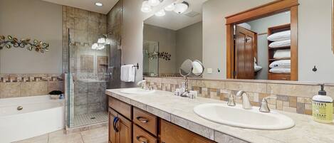 A modern bathroom with a double sink, a glass shower enclosure, and a large mirror.